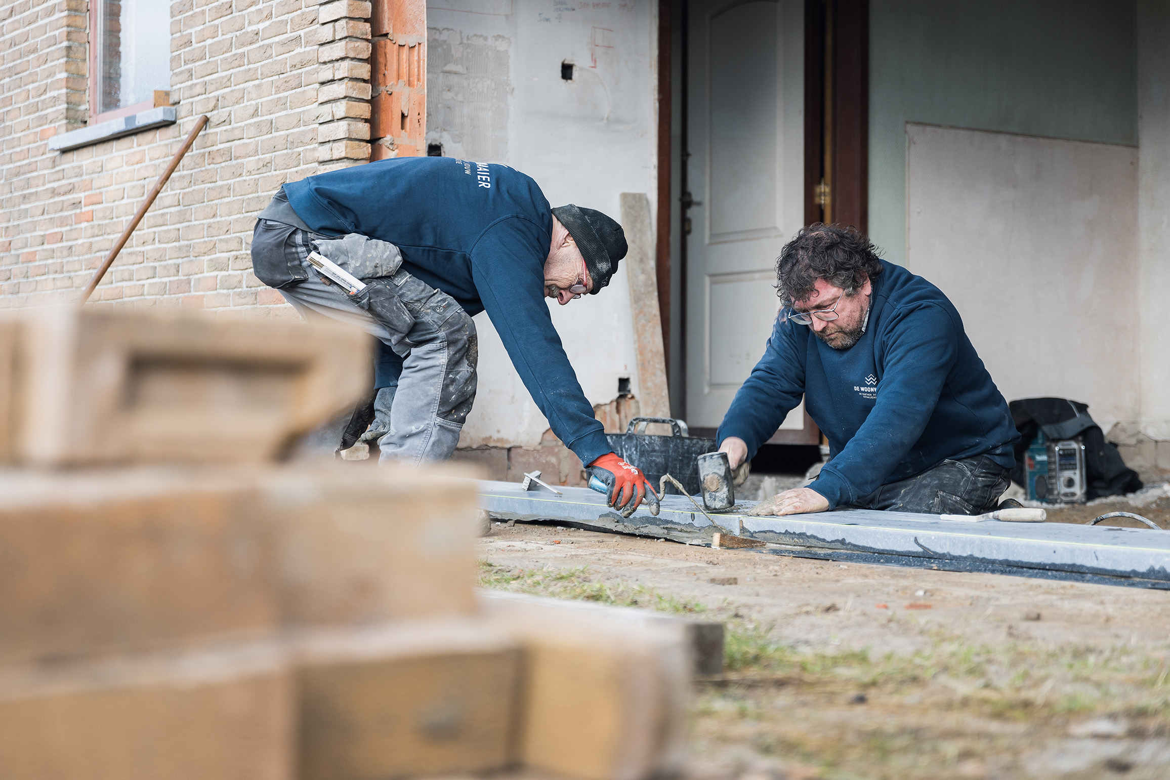 Twee renovatiespecialisten aan het werk op een werf.